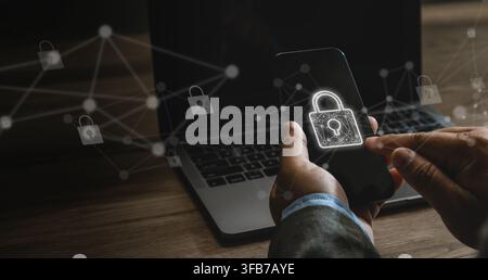Businessman using a smartphone with padlock and network cybersecurity, internet privacy, antivirus protection and secure data across connected devices Stock Photo