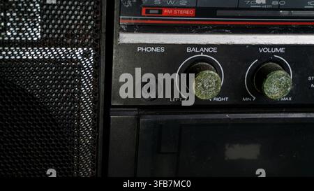 Close up view of an old retro boombox focusing on heavily oxidized volume and balance control knobs with thick green corrosion. The vintage portable a Stock Photo