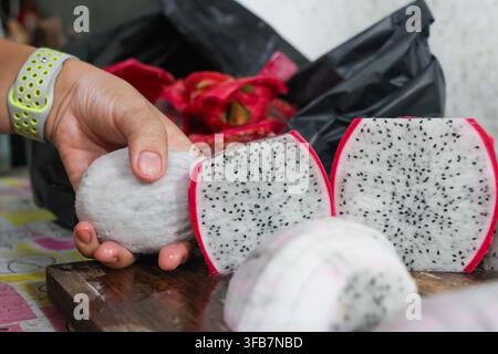 A dragon fruit hand kitchen food preparation cut fruit white flesh black seed red peel close up Stock Photo