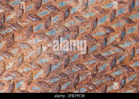 A rusty metal texture with repeating embossed leaf pattern, weathered turquoise and copper surface creating aged industrial background for design proj Stock Photo