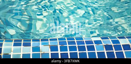 Abstract turquoise pool water with blue mosaic tiles and rippled reflections creating a refreshing aquatic background Stock Photo