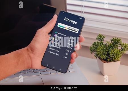 A man holding a smartphone with displaying a storage breakdown menu Stock Photo