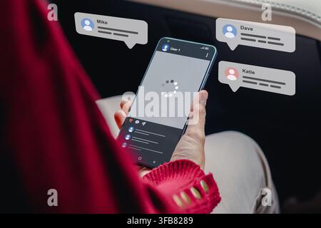 A woman using a smartphone displaying a social media feed with floating chat bubbles Stock Photo