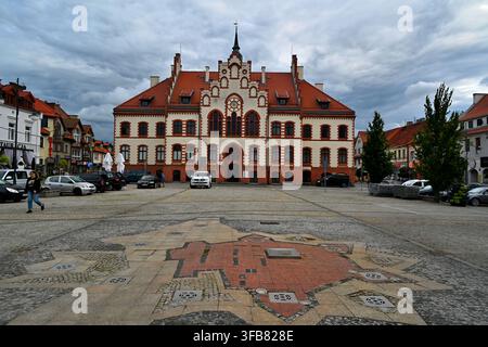 Historic Town Hall Building on Empty Cobblestone Square Under Dramatic Cloudy Sky – the town of Pisz. Stock Photo