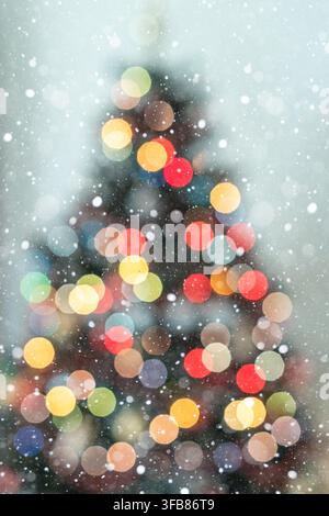 Christmas tree silhouette surrounded by beautiful warm and cool defocused lights on a soft light blue background, with generous copy space for holiday Stock Photo