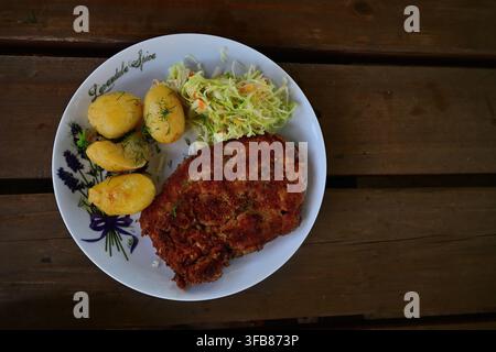 Breaded Cutlet With Boiled Potatoes And Cabbage Salad On A Rustic Wooden Table. Stock Photo