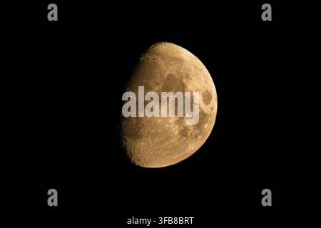 Waxing gibbous moon showing detailed lunar craters against black sky Stock Photo