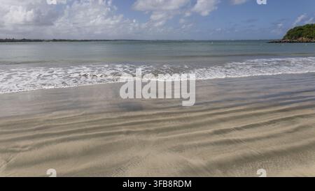 Rolling waves breaking onto a sandy tropical beach Stock Photo