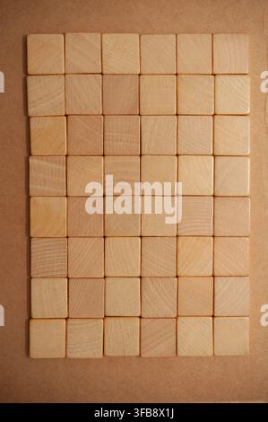 Square wooden blocks arranged in a neat rectangular grid on a brown kraft paper background, viewed directly from above Stock Photo