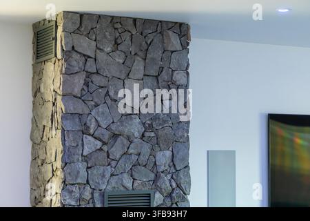 A contemporary living space showcases a striking architectural element with a natural stone column and integrated vents Stock Photo