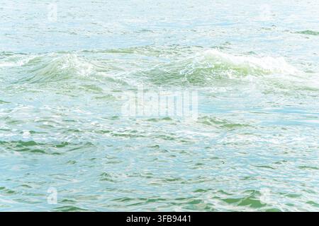 Gentle turquoise ocean waves ripple across a bright sunlit water surface. Stock Photo