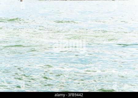 Sunlit ocean water fills the frame with soft rippling wave patterns. Stock Photo