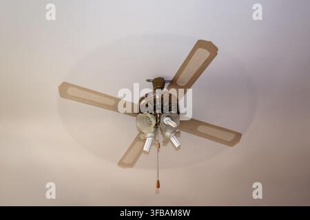 Spinning Ceiling Fan With Motion Blurred Wooden Blades Indoors Stock Photo