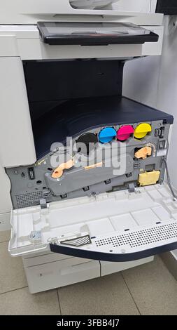 An open office copier showing colorful ink toner cartridges inside the internal maintenance access compartment. Stock Photo