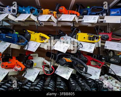 Voronezh, Russia - April 19, 2026.Shelves hold several electric and gas chainsaws in yellow, blue, red, and grey from brands like Huter, Daewoo, and O Stock Photo