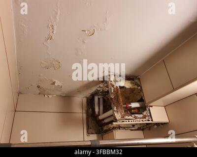The image depicts a severely water-damaged corner of a room, likely a bathroom or utility space, showing significant deterioration of the ceiling and Stock Photo