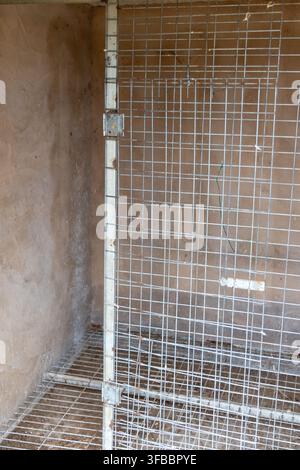 Detailed view of a metallic grid structure adjacent to a textured, earthy-toned wall, suggesting a functional space Stock Photo