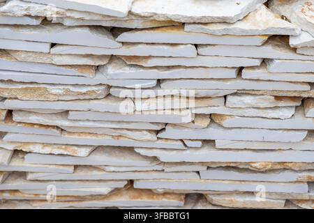 A close-up view of a wall constructed from thin, irregularly shaped natural stone slabs, showcasing a layered pattern and varied textures Stock Photo