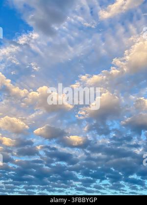 Illuminated cumulus clouds and layered stratocumulus formations against a bright blue sky, Stock Photo