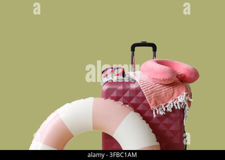 Summer vacation and travel planning, suitcase with beach accessories and inflatable ring on a green background Stock Photo