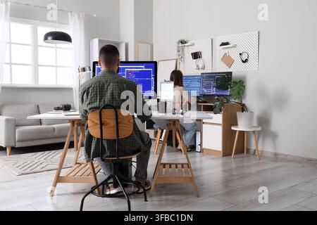 Remote work and software development, two people coding on computers in a modern home office environment Stock Photo