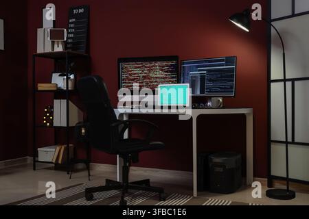 Remote work and coding late at night, empty home office desk with multiple screens showing programming code Stock Photo