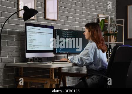 Software development and coding, young woman programmer working on multiple computer screens in a home office Stock Photo