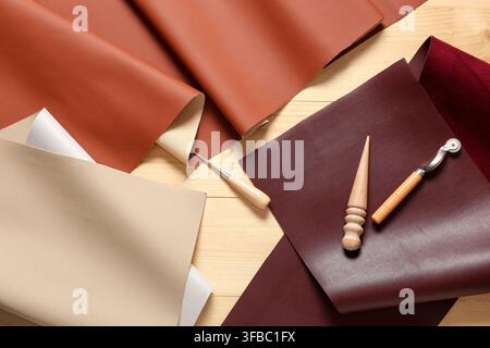 Leather crafting and upholstery materials, various colored faux leather fabric samples with tools on a wooden background Stock Photo