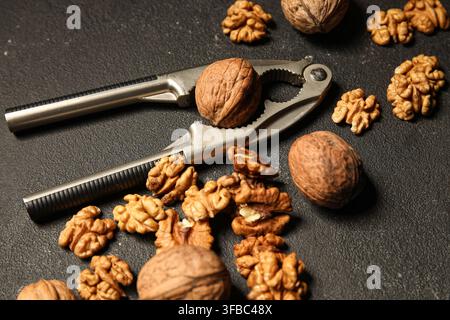 Tasty walnuts and nutcracker on black background Stock Photo