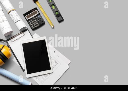 Construction planning and engineering tools digital tablet with blueprints calculator and safety headphones on gray background Stock Photo