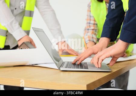 Construction project management and engineering team collaboration, architects working on laptop with blueprints and house model Stock Photo