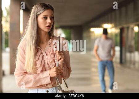 Street harassment and personal safety, young woman feeling unsafe and looking over her shoulder in an urban setting Stock Photo