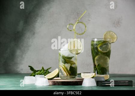 Glasses of fresh Mojito cocktail with mint and ice cubes on green table Stock Photo