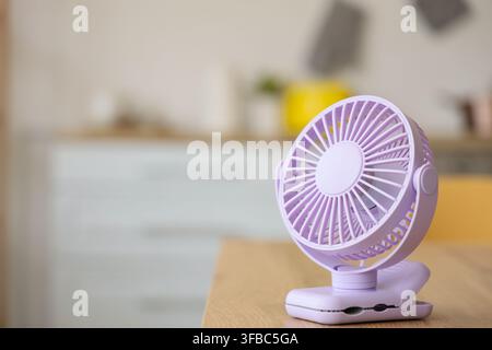 Lilac mini fan on table in kitchen, closeup Stock Photo