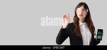 Augmented reality and online banking, woman in smart glasses interacting with virtual interface and holding smartphone Stock Photo