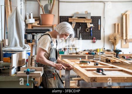 Handwork, skills and craftsmanship in restoration business, focused man restorer repairs wooden door Stock Photo