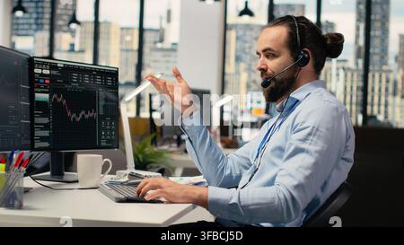 Financial advisor in office offers personalized investment guidance during live calls with clients. Consultant talking in headset mic, helping customers build tailored portfolio Stock Photo