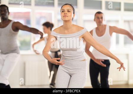 Concentrated women and men rehearsing ballet dance in class Stock Photo