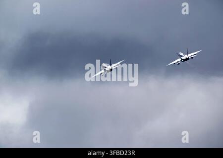 Military fighter jets flying in formation through cloudy sky. Stock Photo