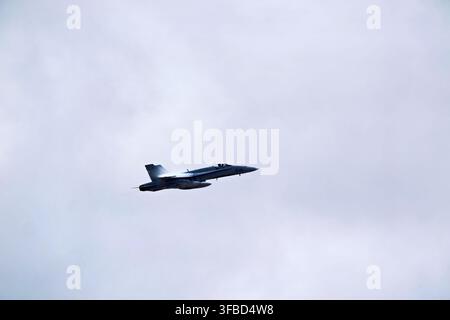Military jet flying in cloudy sky. Stock Photo