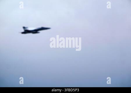 Military jet flying in cloudy sky. Stock Photo
