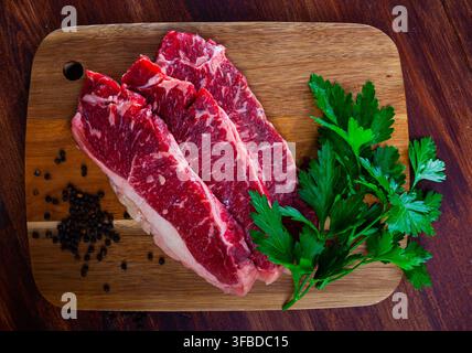 Raw marbled beef steaks with herbs and condiments Stock Photo