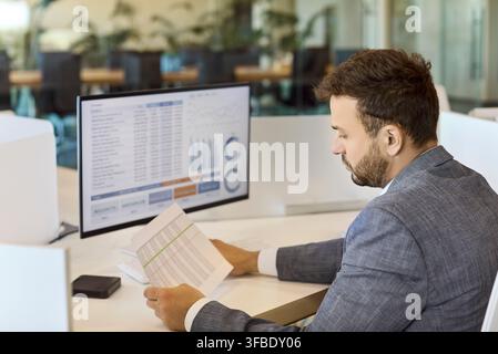 Accountant reviewing financial report on computer in modern corporate office Stock Photo