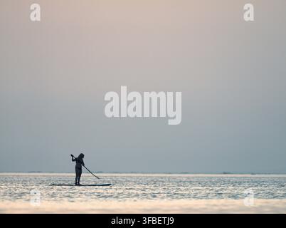 Lone paddle boarder on a hazy sea horizon Stock Photo