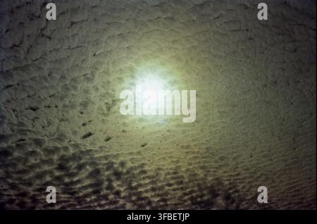 Sun Glowing Through Dense Textured Clouds Stock Photo