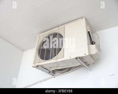 Air conditioner unit mounted on a white wall Stock Photo