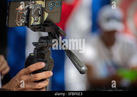 Smartphone mounted on a tripod records live coverage at El Carnavalito in Ciego de Ávila, Cuba, on August 21, 2026. Stock Photo
