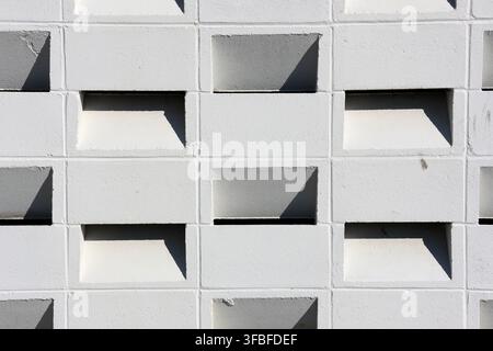 Full frame texture background of a white breeze block wall featuring clean geometric shapes and strong sunlight shadows Stock Photo