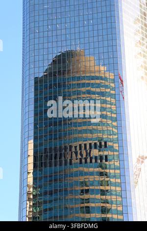 Distorted reflection of a neighbouring skyscraper visible on the curved glass facade of a modern city high-rise Stock Photo