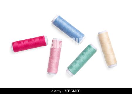 Five sewing thread spools, randomly distributed against a plain white background. Vibrant and colorful polyester sewing thread, wound onto paper rolls Stock Photo